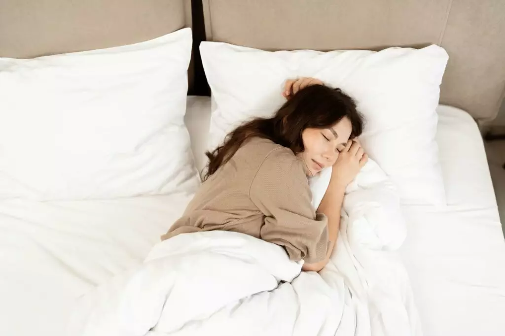 Young Woman Sleeping Peacefully In Cozy White Bed