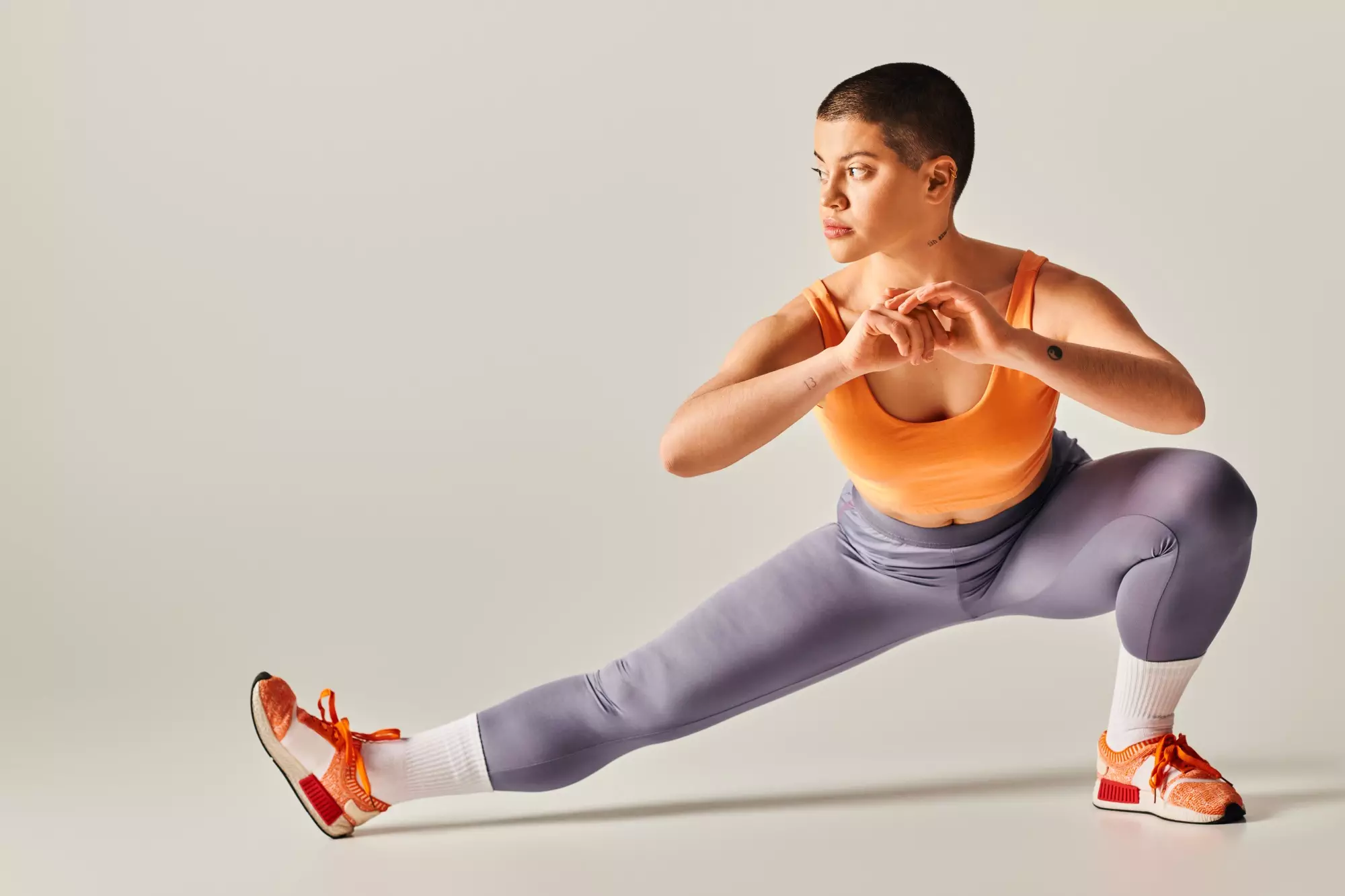 self-esteem, body positivity, flexible and short haired woman stretching legs on grey background,