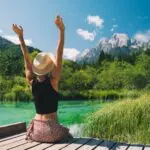 People in nature. Tourist woman with raised arms up in green nature background.